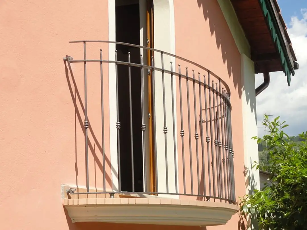 Ringhiera in ferro curva su un balcone di una casa rosa