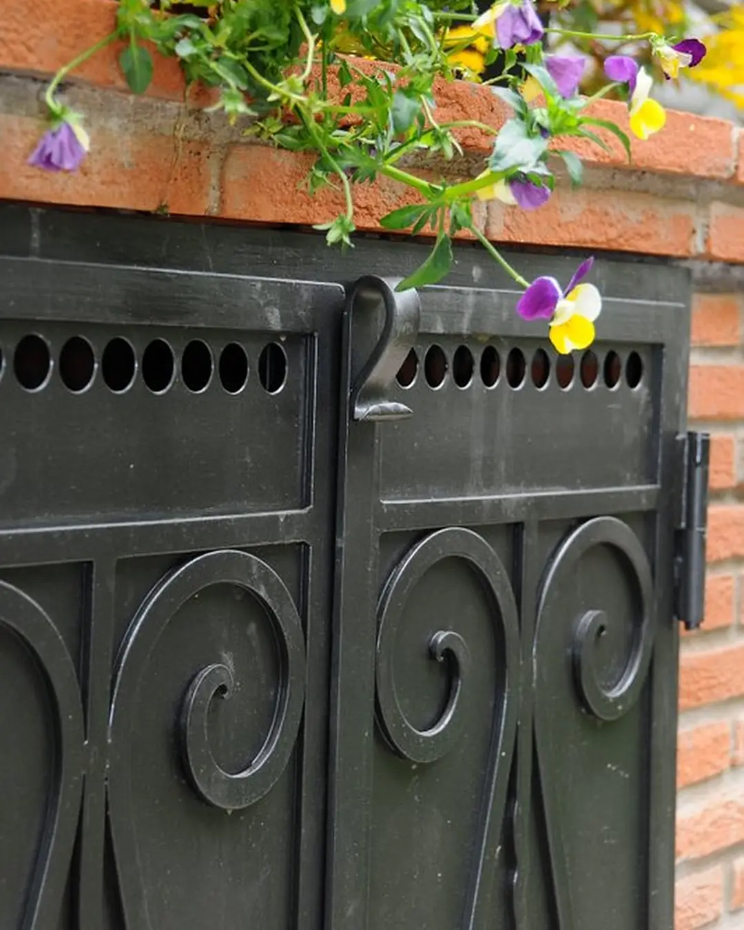 Particolare di una porta in ferro battuto con riccioli, sotto una fioriera